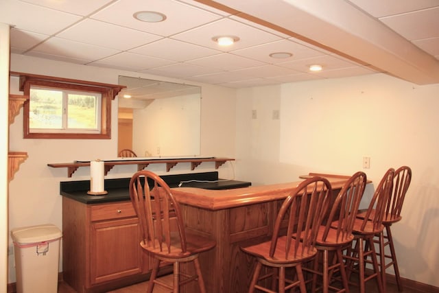 bar with recessed lighting, a bar, a paneled ceiling, and baseboards