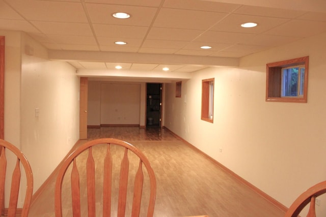 corridor with recessed lighting, baseboards, light wood finished floors, and a paneled ceiling