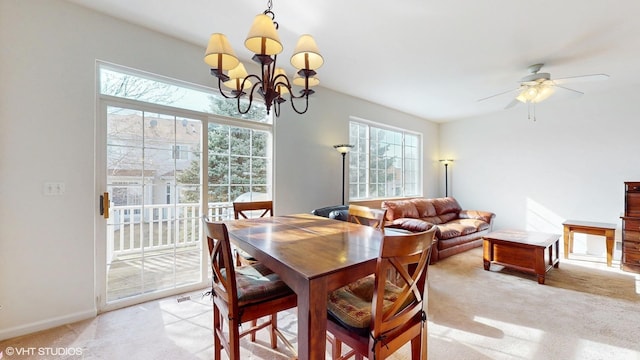 dining area featuring baseboards, plenty of natural light, light colored carpet, and ceiling fan with notable chandelier