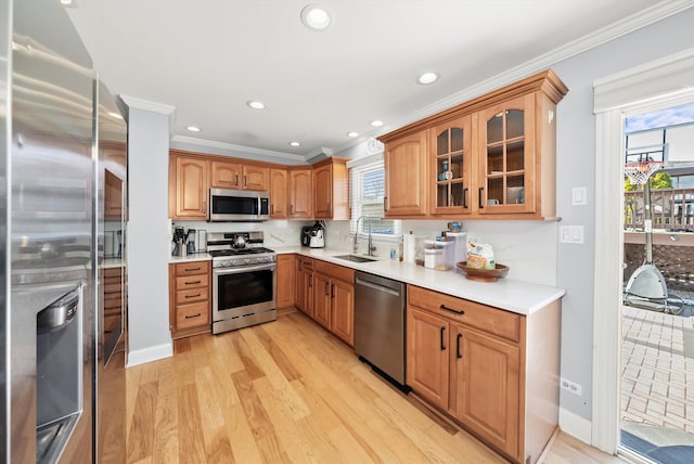 kitchen featuring light wood-style flooring, glass insert cabinets, appliances with stainless steel finishes, and a sink