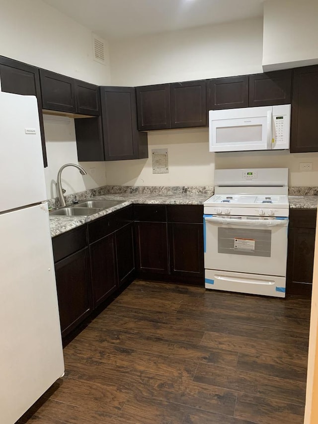 kitchen featuring a sink, visible vents, white appliances, and dark wood finished floors