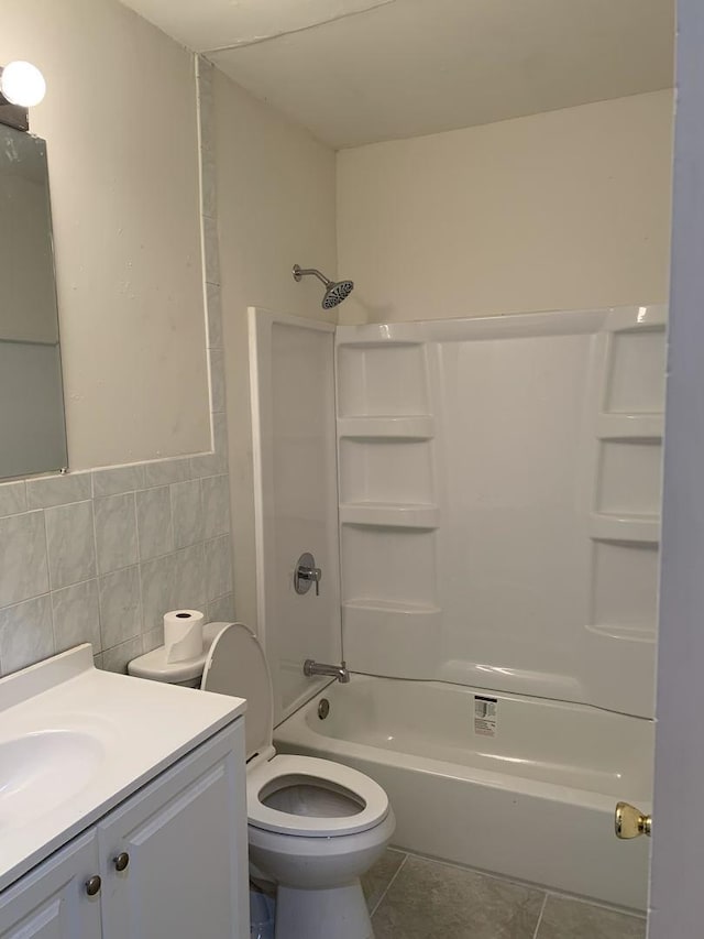 bathroom with toilet, vanity, tile patterned floors, tile walls, and  shower combination