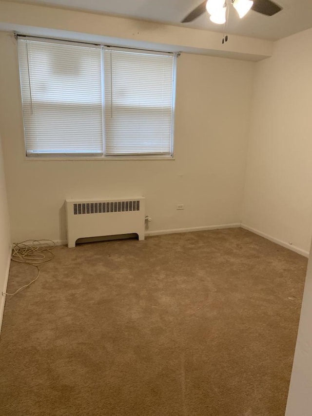 carpeted empty room with baseboards, radiator heating unit, and ceiling fan