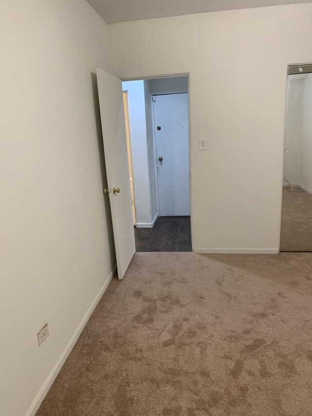 carpeted spare room featuring baseboards