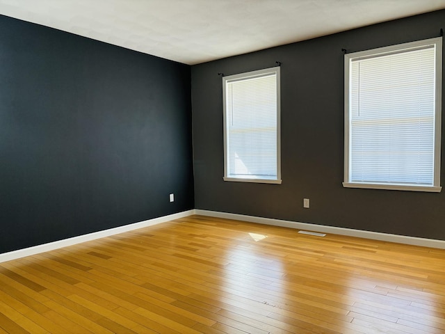 unfurnished room with baseboards, visible vents, and light wood-type flooring