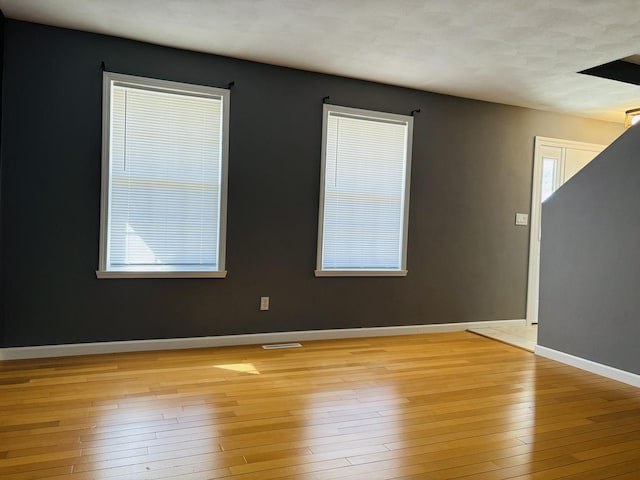 empty room featuring light wood-style flooring, baseboards, and visible vents