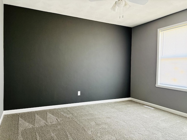 unfurnished room with visible vents, baseboards, carpet, and a ceiling fan