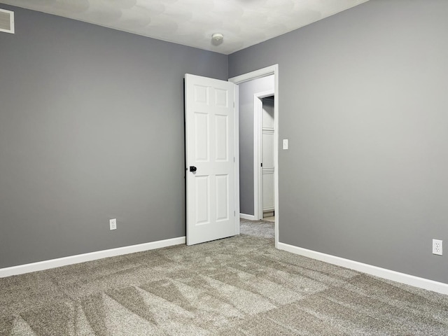 spare room with visible vents, carpet, and baseboards