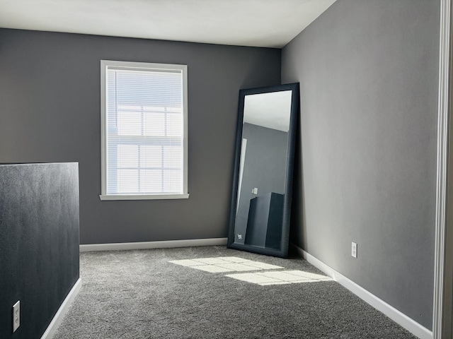 carpeted spare room featuring baseboards