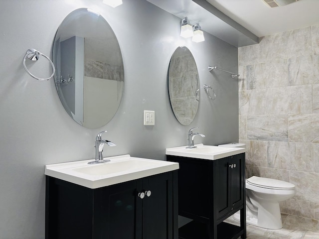 full bath featuring a sink, visible vents, toilet, and two vanities