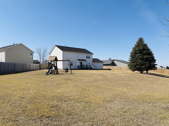 rear view of property featuring a playground, a lawn, and fence