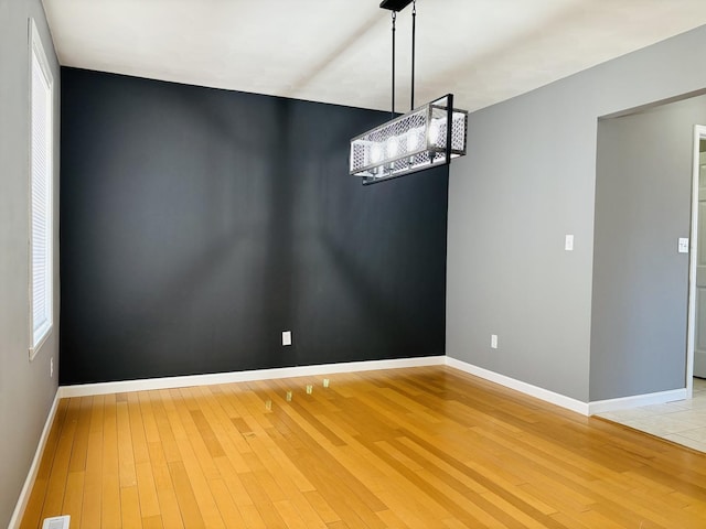 unfurnished dining area featuring hardwood / wood-style floors and baseboards