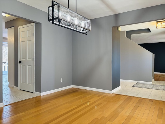 unfurnished dining area featuring baseboards, light wood-style floors, and a chandelier