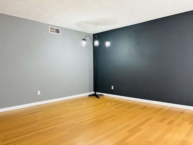 spare room with light wood-style flooring, baseboards, and visible vents