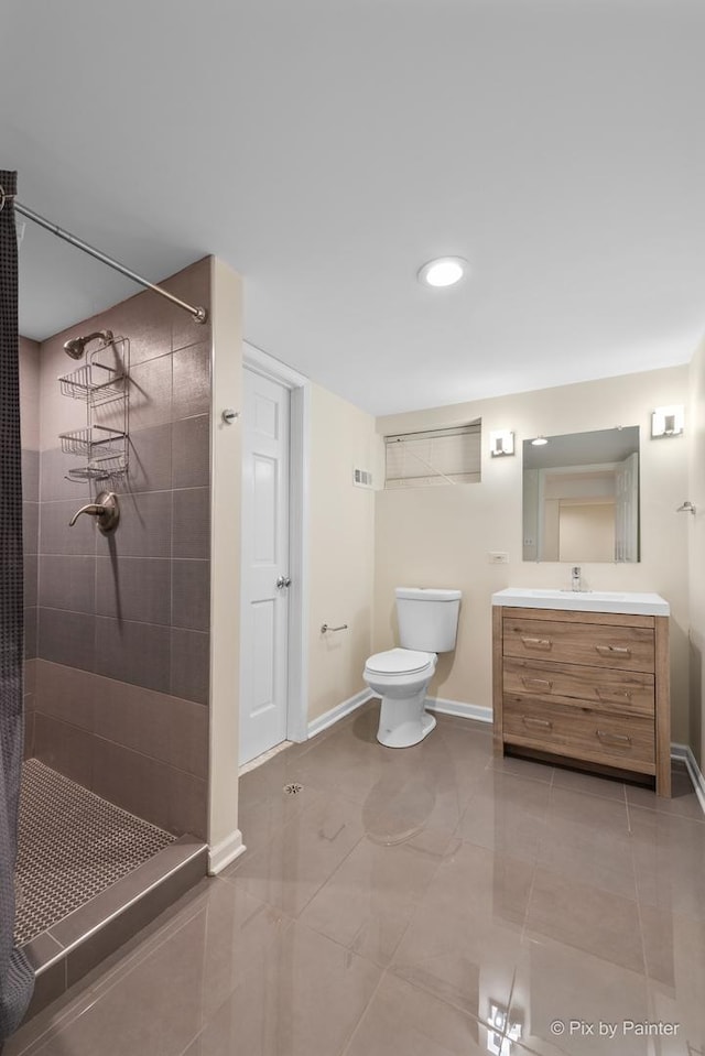 full bath featuring vanity, toilet, baseboards, and tiled shower