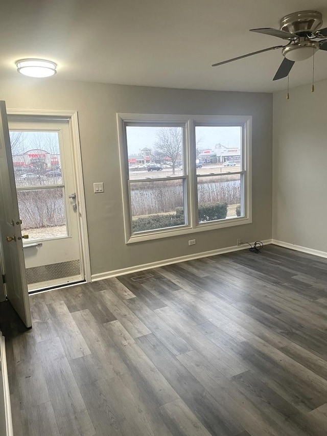 interior space with dark wood-style floors, ceiling fan, and baseboards