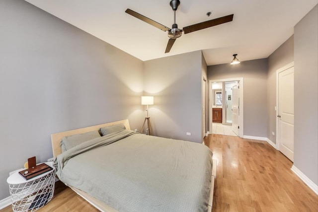 bedroom with light wood-type flooring, baseboards, a ceiling fan, and ensuite bathroom