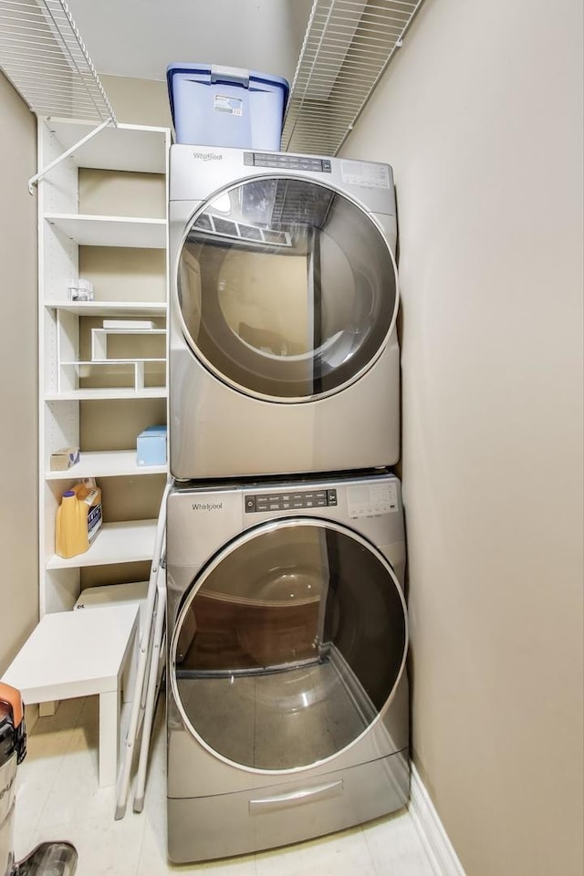 laundry area with tile patterned flooring, baseboards, laundry area, and stacked washing maching and dryer