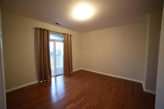 unfurnished room with visible vents, baseboards, and dark wood-style floors