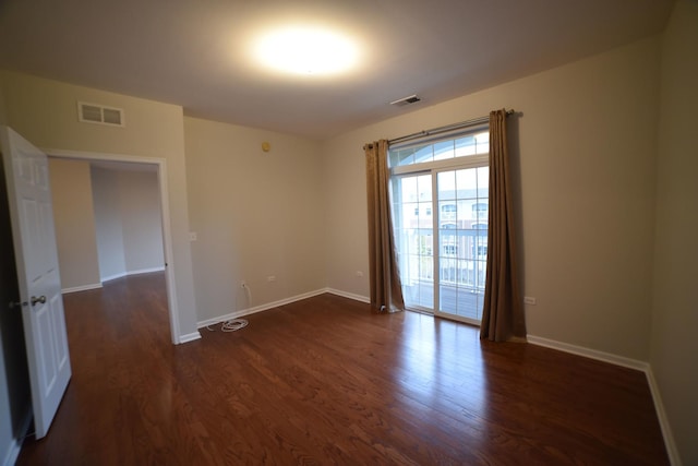 empty room featuring dark wood finished floors, baseboards, and visible vents