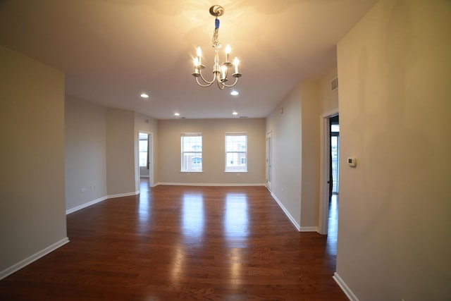 unfurnished room with baseboards, dark wood-type flooring, and an inviting chandelier