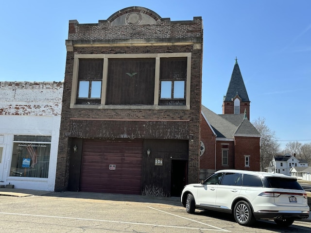 view of front of property featuring brick siding, an attached garage, and driveway