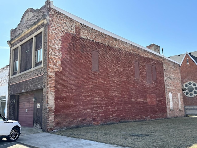 view of property exterior with brick siding and a lawn