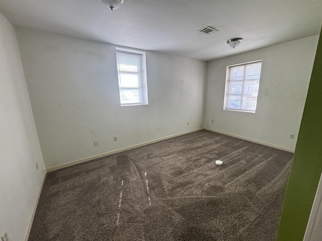 carpeted empty room with visible vents, baseboards, and a healthy amount of sunlight