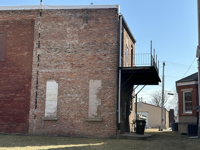 view of side of home featuring a yard, central AC unit, and brick siding