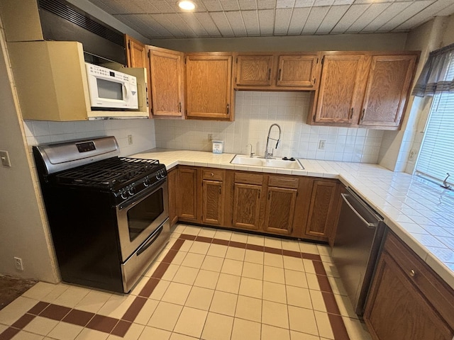 kitchen featuring tasteful backsplash, tile countertops, recessed lighting, appliances with stainless steel finishes, and a sink