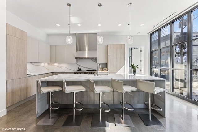 kitchen featuring light stone countertops, decorative backsplash, expansive windows, wall chimney range hood, and modern cabinets