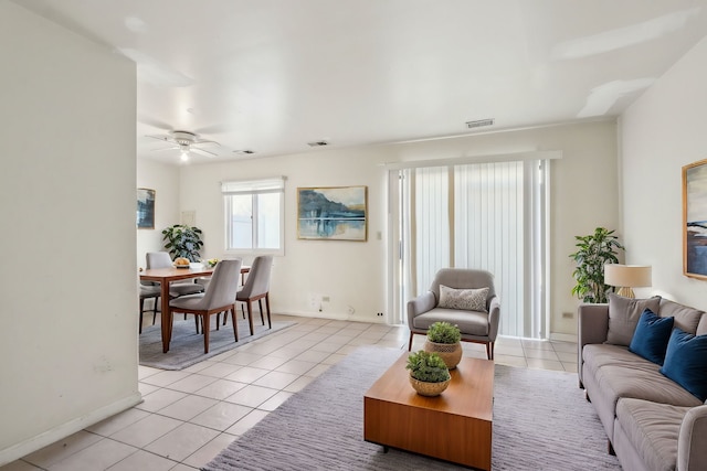 living area featuring light tile patterned flooring, visible vents, and ceiling fan