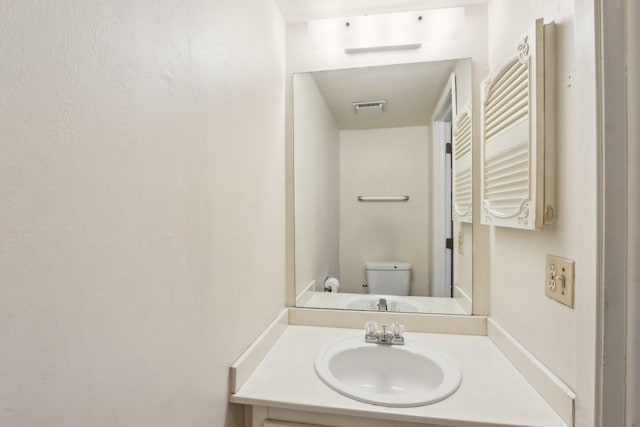 bathroom with visible vents, vanity, toilet, and radiator heating unit