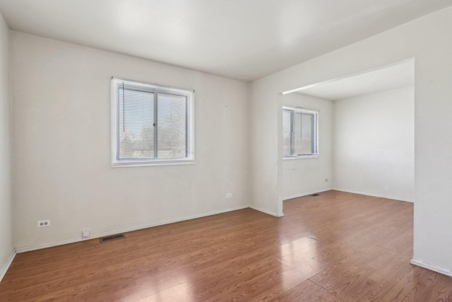 unfurnished room with visible vents, baseboards, and wood finished floors