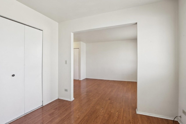 unfurnished bedroom featuring wood finished floors, a closet, and baseboards