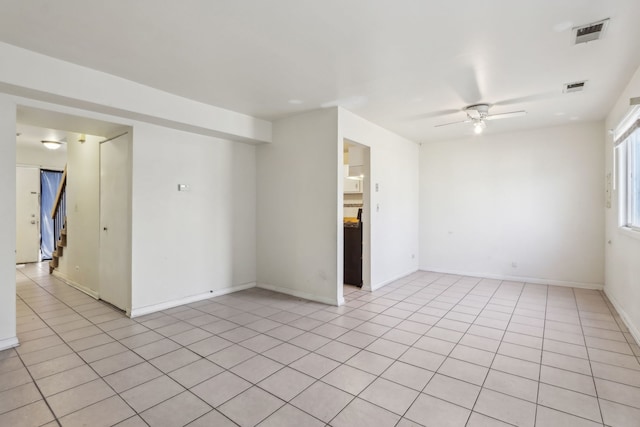 spare room with stairs, light tile patterned flooring, a ceiling fan, and visible vents