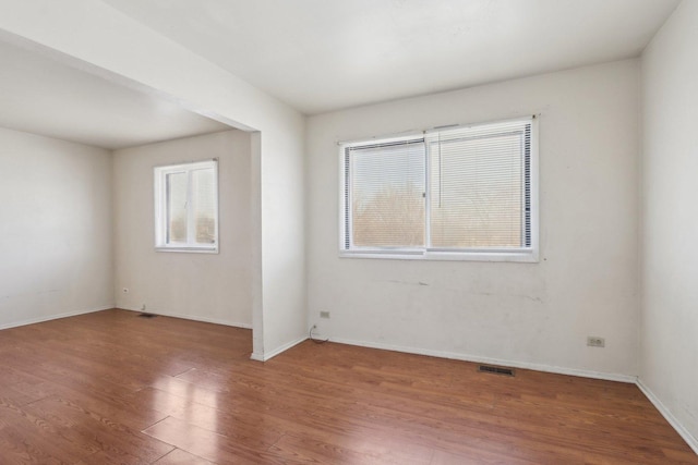 empty room featuring visible vents, baseboards, and wood finished floors