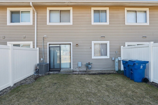 back of house featuring cooling unit, a yard, and fence