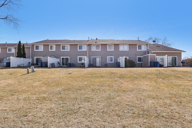 rear view of house featuring a yard and fence