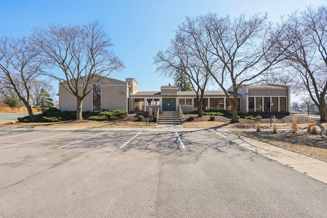 view of front of home with uncovered parking and a sunroom