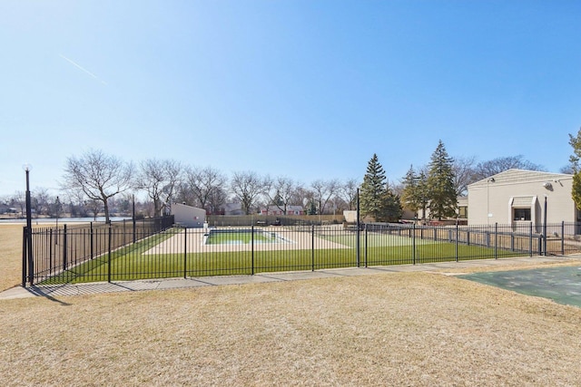 view of basketball court featuring a lawn and fence