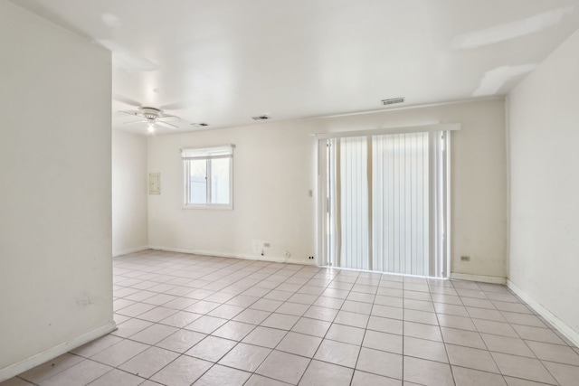 empty room featuring light tile patterned floors, visible vents, baseboards, and ceiling fan