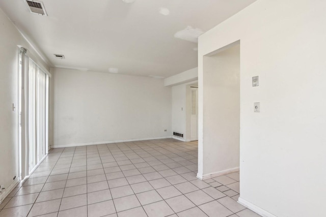 empty room with light tile patterned floors, visible vents, and baseboards