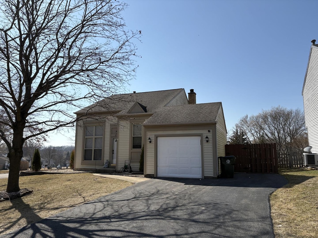 view of front of property with a shingled roof, fence, aphalt driveway, a chimney, and an attached garage