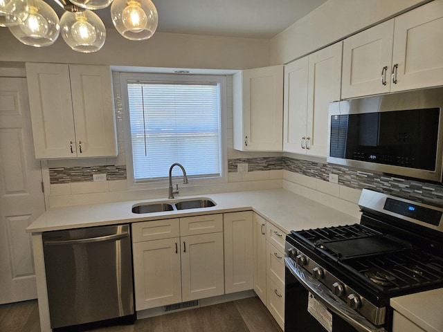 kitchen featuring a sink, tasteful backsplash, dark wood finished floors, stainless steel appliances, and white cabinets