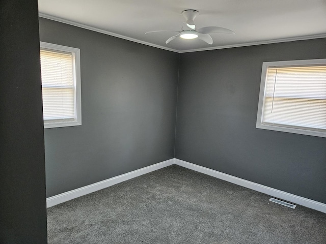 spare room with a wealth of natural light, baseboards, visible vents, and dark colored carpet