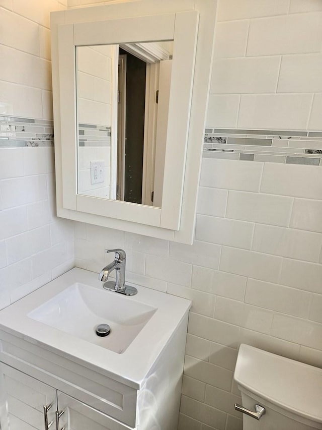 half bathroom with toilet, vanity, and tile walls