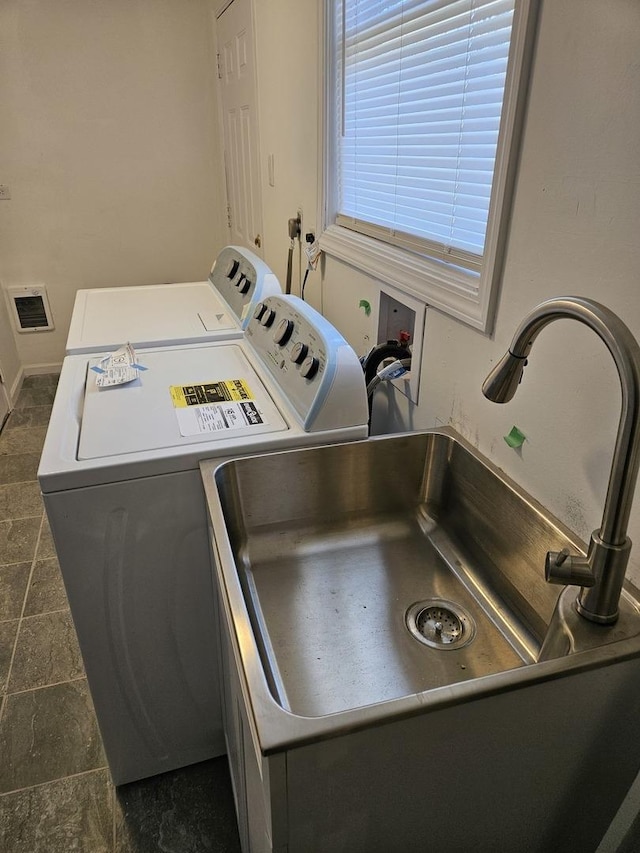 laundry area with a sink, laundry area, stone finish flooring, and washer and clothes dryer