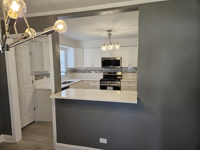 kitchen with a sink, stainless steel appliances, white cabinets, light countertops, and decorative backsplash