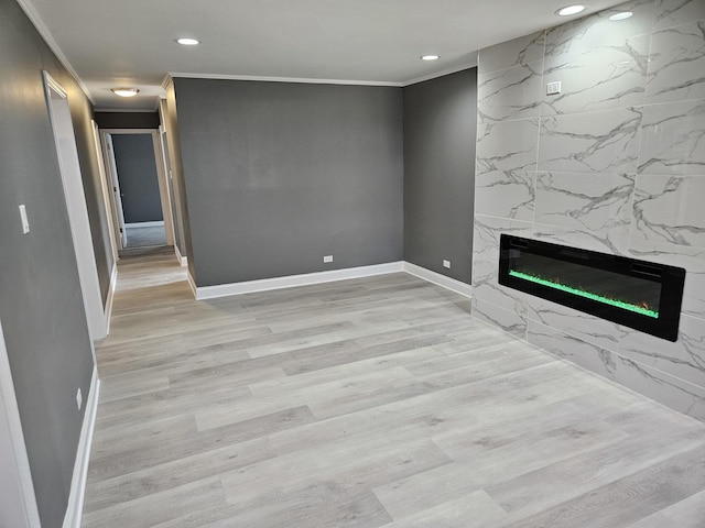 unfurnished living room featuring ornamental molding, recessed lighting, a fireplace, light wood finished floors, and baseboards